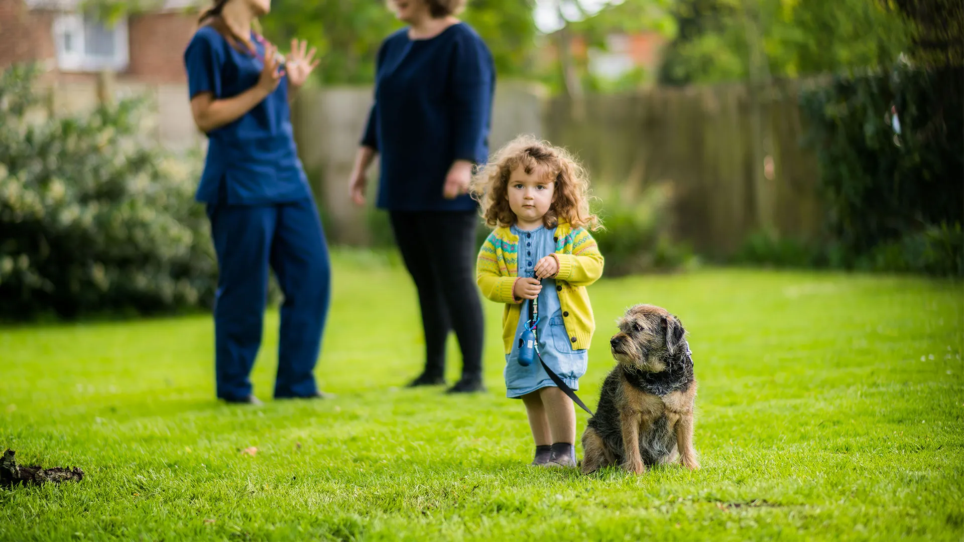 child holding dog on lead in garden