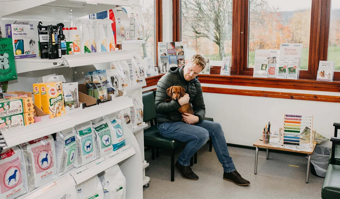 client sitting with small dog in veterinary waiting room