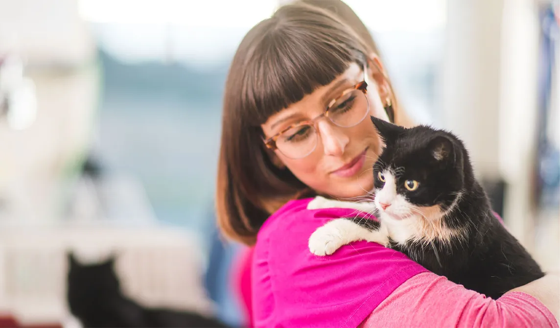 Nurse in pink holding black and white cat