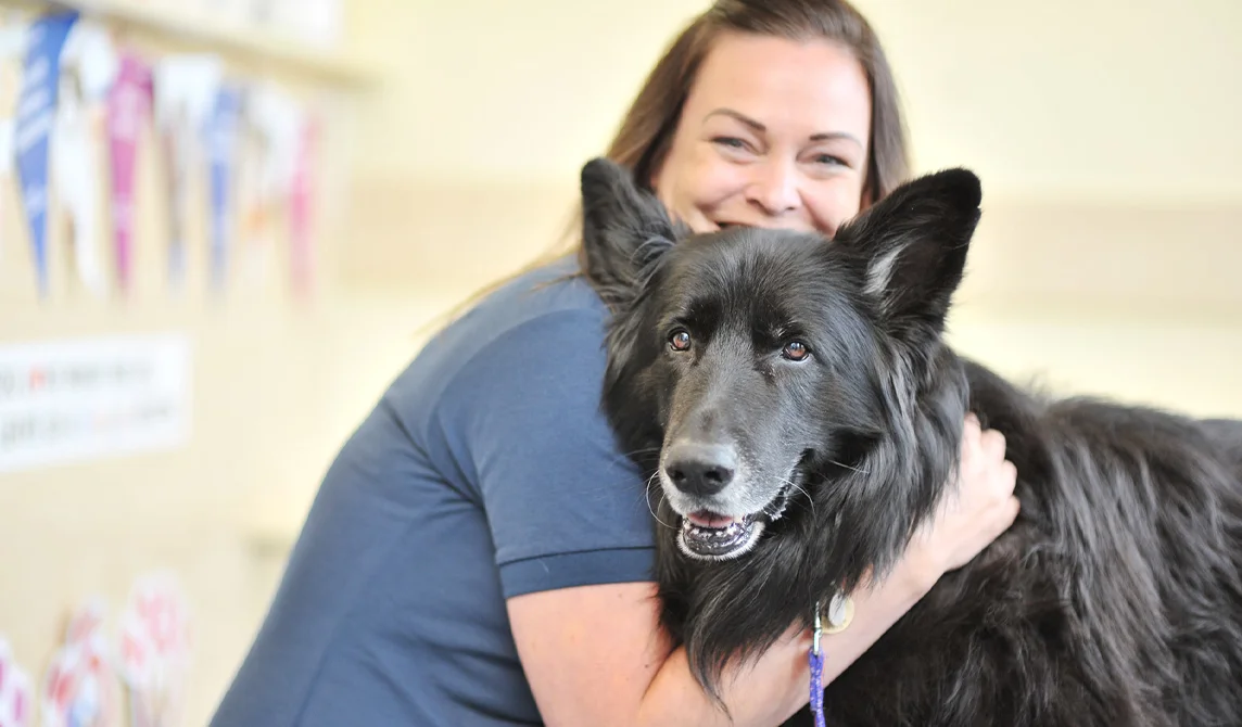 Smiling nurse holding black dog