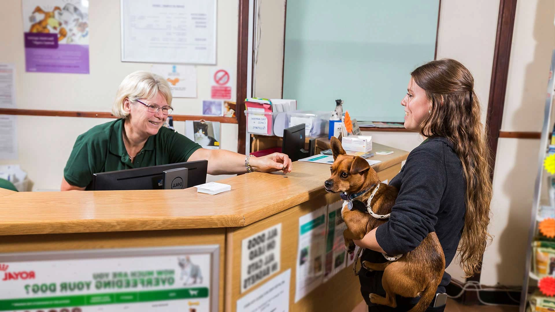 Receptionist welcoming client with dog